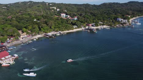 Rotating-aerial:-Tourist-boats-return-to-pier,-Caribbean-Roatan-shore