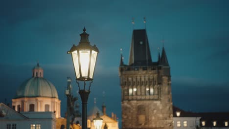 Charles-Bridge,-glowing-street-lamp,-Old-Town-Bridge-Tower-backdrop,-Prague