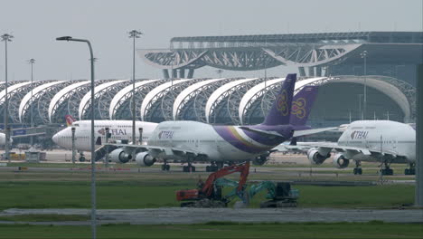 Eine-Reihe-Von-Flugzeugen-Der-Thai-Airways,-Der-Offiziellen-Fluggesellschaft-Thailands,-Parken-Auf-Dem-Rollfeld-Des-Flughafens-Suvarnabhumi-Und-Warten-Darauf,-Dass-Sie-An-Die-Reihe-Kommen