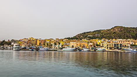 Timelpase-over-water,-docked-boats,-yellow-and-orange-buildings