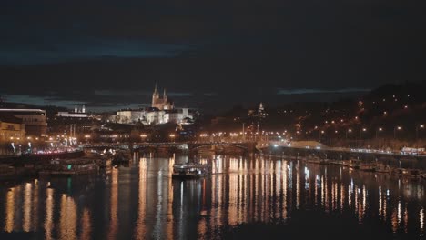 Vista-Nocturna-De-Praga-Desde-El-Puente-Stefanik,-El-Río,-El-Castillo-Iluminado-Y-Los-Barcos.