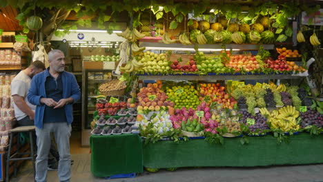 Owner-of-fresh-fruit-and-vegetables-stands-by-his-colourful-market-stall