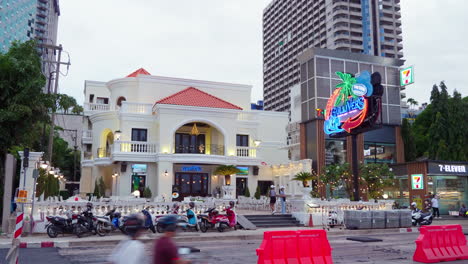 A-busy-street-undergoing-construction-in-front-of-a-famous-pub-and-restaurant,-a-convenience-store,-condominiums,-hotels,-and-other-business-establishments-at-Pattaya-in-Chonburi-province-in-Thailand