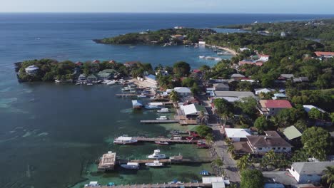 Aerial:-Boat-docks-jut-into-pristine-Caribbean-water,-reefs-on-Roatan