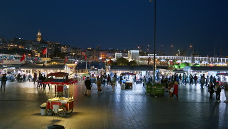 Busy-city-night-scene-at-Eminonu-Pier-with-illuminated-Galata-Tower