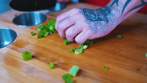 Chopped-onions-being-tossed-by-a-tattooed-hand-on-a-chefs-cutting-board