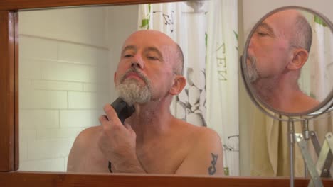 Caucasian-male-using-electrical-trimmer-to-cut-his-hair-and-beard