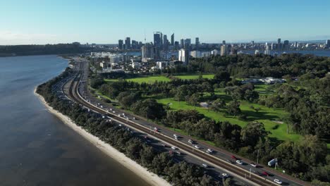 Aerial-establishing-shot-of-traffic-on-coastline-Highway-and-skyline-of-Perth-City-in-background-at-sunny-day-with-blue-sky---Wide-shot