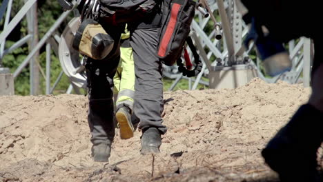 Low-angle-close-up-shot-of-electricians-in-protective-gear-as-they-walk-through-drying-earth-to-repair-a-power-pole