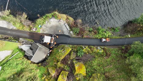 Workers-putting-new-asphalt-on-Norway-countryside-road-by-the-sea---Top-down-aerial-above-machinery-and-workers
