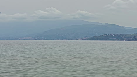 Time-Lapse-static-shot-of-the-beautiful-calm-sea-off-the-italian-coast-of-sicily-in-italy-with-view-of-the-passing-clouds-and-the-mountains-in-the-background