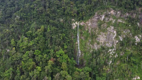Aerial-approaches-tall,-vine-like-waterfall-in-Honduras-wild-mountains