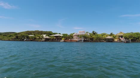 From-a-boat,-affluent-waterfront-homes-on-coast-of-Roatan,-Honduras