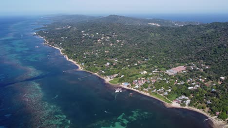 Tropical-north-coast-of-Punta-Gorda,-Roatan-Honduras,-high-aerial-view