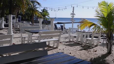 Pan-across-wood-tables-and-benches-at-beach-restaurant-in-Roatan,-HND