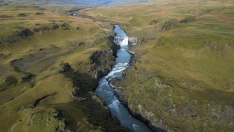 Waterfall-and-River-in-Green-Southeast-Iceland-Countryside,-Aerial-Drone-View