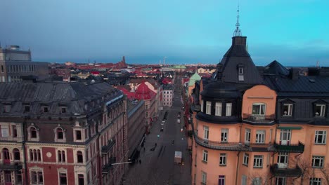 Drone-shot-revealing-the-cityscape-of-Stockholm-old-town,-Colourful-Swedish-buildings-architecture-with-busy-streets,-Cathedral-in-the-evening