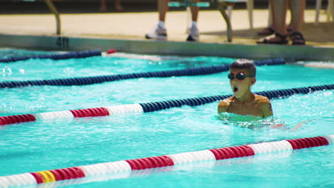 Young-boy-dives-off-block-in-swimming-competition,-breaststroke---tracking-shot