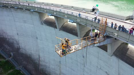 Staff-at-bungee-jumping-Platform-setting-up-woman-to-jump-while-People-on-Dam-bridge-watching-in-Austria