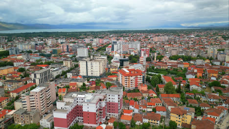 Aerial-drone-forward-moving-shot-over-city-buildings-and-houses-in-Shkodra,-also-known-as-Shkoder-or-Scutari-in-northwestern-Albania-on-a-cloudy-day