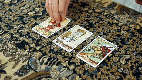 A-woman-giving-a-tarot-reading-with-the-page-of-cups-the-ace-of-swords-and-the-knight-of-swords-cards