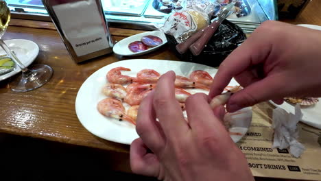 Cleaning-prawns:-Close-up-shot-of-hands-removing-the-head-and-shell-of-prawn-after-been-cooked