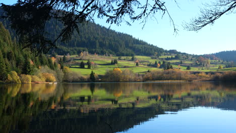 Mountain-lake-with-calm-water-surface-in-autumn-day