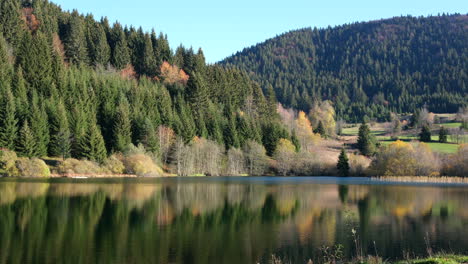 Mountain-lake-in-autumn-day-surrounded-with-pine-forest
