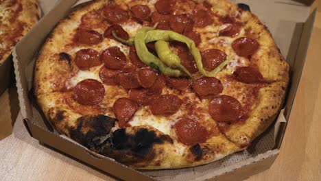 Rotierende-Aufnahme-Köstlicher-Italienischer-Pizzen,-Die-In-Kartons-Auf-Dem-Tisch-Geliefert-Werden,-Pizza-Mit-Verbrannter-Kruste