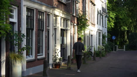 A-Young-Man-Is-Walking-Along-The-Empty-Spieringstraat-In-Gouda,-South-Holland,-Netherlands