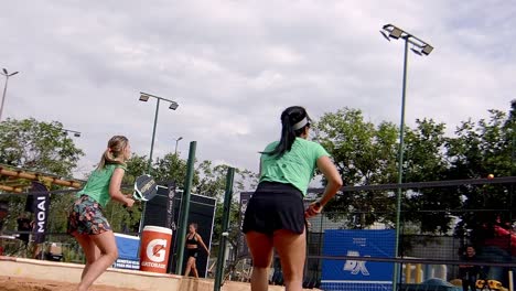 woman-in-shorts-playing-padel-game-in-sunny-beachcourt,-fast-gameplay,-slowmotion-shot