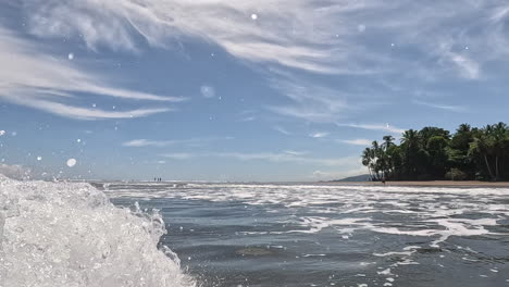 Big-wave-splashing-over-camera-with-view-of-tropical-beach-in-Costa-Rica