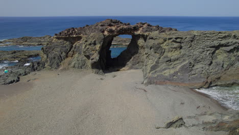 Fuerteventura-Island,-Ajui:-aerial-view-traveling-in-over-the-Jurado-arch-on-a-sunny-day-with-beautiful-colors