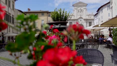 View-on-The-picturesque-square-"Piazza-del-Mercato"-in-Spoleto,-a-city-of-Umbria-with-terraces,-flowers-and-an-ancient-building-with-a-clock-and-a-fountain-on-its-façade