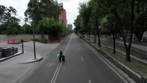 Drone-shot-of-an-avenue-in-Mexico-City-completely-empty-with-a-person-carrying-a-suitcase