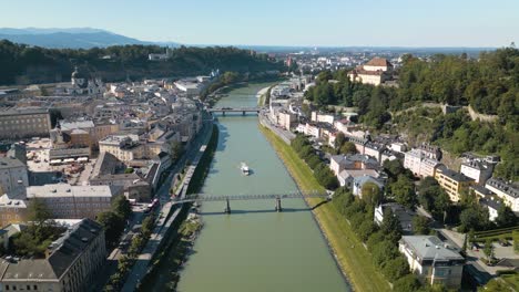 Drone-Descends-to-Reveal-Pedestrian-Bridge-over-River-Salzach-in-Salzburg,-Austria