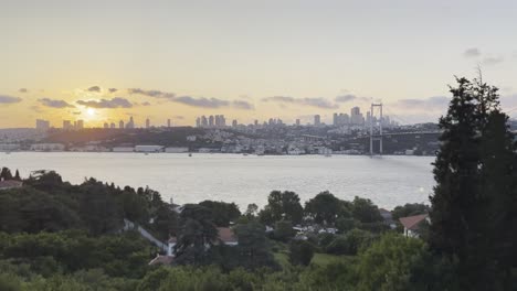 Istanbul-Bosphorus-Bridge-at-sunset,-sun-drops-slowly-behind-Turkish-skyline