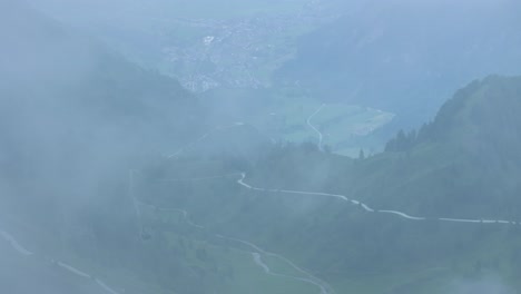 As-fog-clears-the-beautiful-Austrian-landscape-below-is-revealed,-aerial