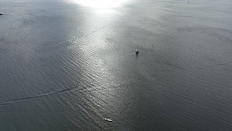 Lonely-sailboat-at-sea-in-the-Danish-sunset---High-angle-aerial-looking-down-at-boat-in-Aarhus-Denmark