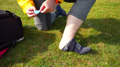Hiker-takes-off-sock-to-put-adhesive-pad-to-prevent-heel-chafing