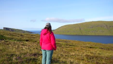 Woman-stops-walking-to-admire-scenery-near-Lake-Sorvagsvatn,-Faroe-Islands