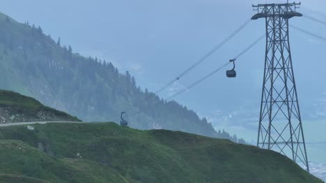 Occupants-being-transported-by-cable-cars-above-green-mountainous-landscape