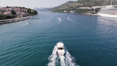 Aerial-Tracking-shot:-boat-sailing-Dubrovnik-port,-Adriatic-Sea-backdrop