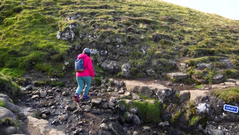 Mujer-Cruzando-Un-Pequeño-Arroyo-Con-Rocas,-Continuando-La-Caminata-En-El-Lago-Sorvagsvatn