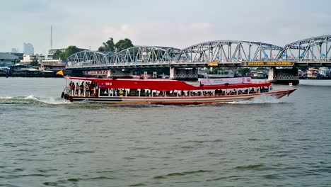 A-water-bus-is-about-to-pass-beneath-the-Krung-Thon-Bridge-spanning-the-Chao-Phraya-river,-a-gateway-to-major-tourist-attractions-in-Bangkok,-Thailand