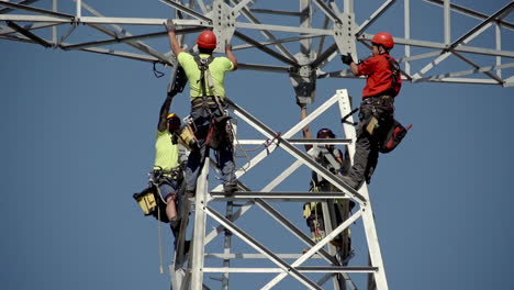 Handheld-shot-of-electricians-secured-with-safety-gear-and-safety-helmets-while-doing-hazardous-repair-work-on-power-lines-secured-from-a-utility-pole-at-height