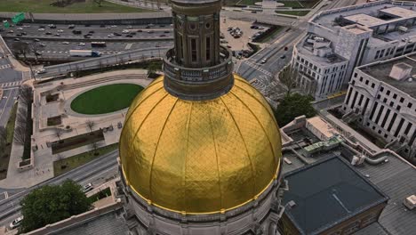 Luftaufnahme-Nach-Oben,-Die-Die-Goldene-Kuppel-Des-Georgia-Capitol-Museum-Mit-Verkehr-Auf-Der-Autobahn-In-Atlanta-Während-Der-Goldenen-Stunde-Zeigt