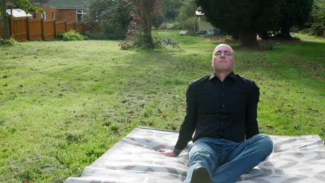 Ein-Mann-Entspannt-Sich-Draußen-Und-Sitzt-Mit-Geschlossenen-Augen-In-Einem-Garten-Auf-Einer-Matte