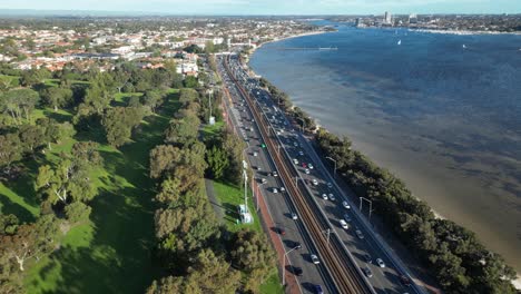 Aerial-top-down:-Busy-Traffic-on-coastal-road-beside-Swan-River-in-Perth-City-at-sunset---panning-shot