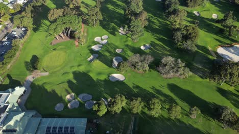 Aerial-tilt-down-showing-golf-course-with-sand-and-trees-during-sunny-day-in-Perth